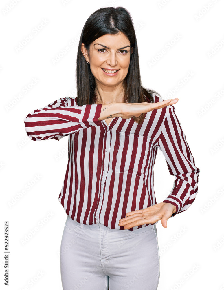 Beautiful brunette woman wearing striped shirt gesturing with hands showing big and large size sign, measure symbol. smiling looking at the camera. measuring concept. Beautiful brunette woman wearing striped shirt gesturing with hands showing big and large size sign, measure symbol. smiling looking at the camera. measuring concept.