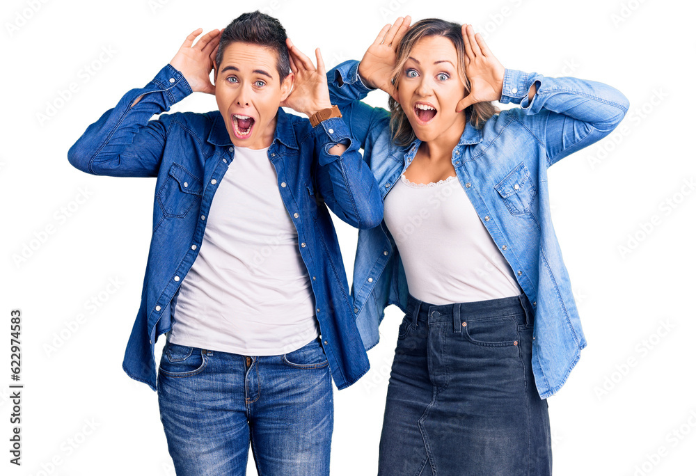 Couple of women wearing casual clothes smiling cheerful playing peek a boo with hands showing face. surprised and exited Couple of women wearing casual clothes smiling cheerful playing peek a boo with hands showing face. surprised and exited