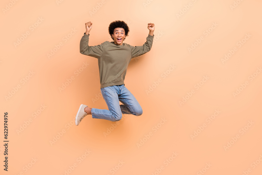 Full body size photo of young overjoyed guy celebrate victory competition fists up hooray wear stylish apparel isolated on beige color background