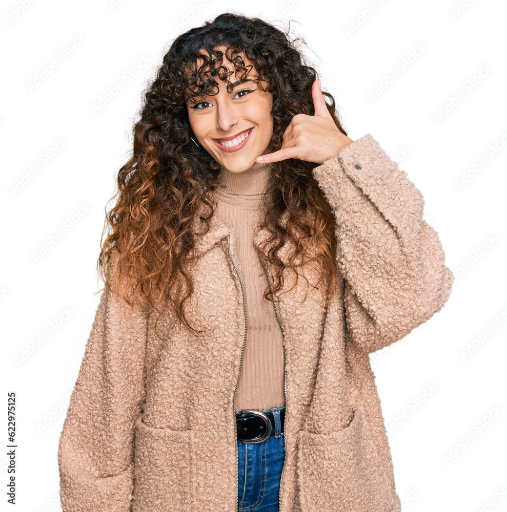 Young hispanic girl wearing winter clothes smiling doing phone gesture with hand and fingers like talking on the telephone. communicating concepts. Young hispanic girl wearing winter clothes smiling doing phone gesture with hand and fingers like talking on the telephone. communicating concepts.