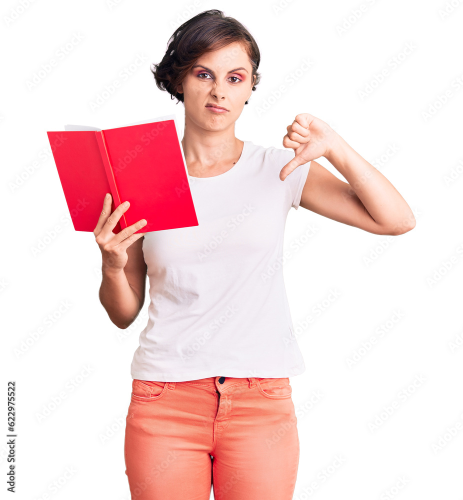 Beautiful young woman with short hair reading a book with angry face, negative sign showing dislike with thumbs down, rejection concept Beautiful young woman with short hair reading a book with angry face, negative sign showing dislike with thumbs down, rejection concept