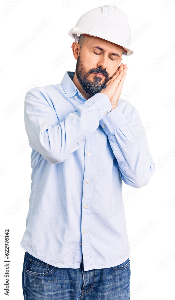 Young handsome man wearing architect hardhat sleeping tired dreaming and posing with hands together while smiling with closed eyes. Young handsome man wearing architect hardhat sleeping tired dreaming and posing with hands together while smiling with closed eyes.