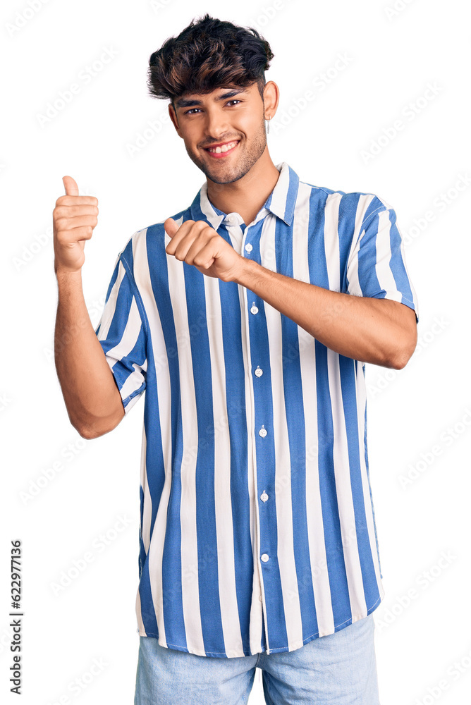 Young hispanic man wearing casual clothes pointing to the back behind with hand and thumbs up, smiling confident Young hispanic man wearing casual clothes pointing to the back behind with hand and thumbs up, smiling confident