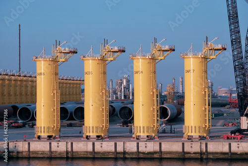 Brand new offshore wind monopile foundations in the Dutch port. Offshore wind power generation. Alternative source of energy. photo