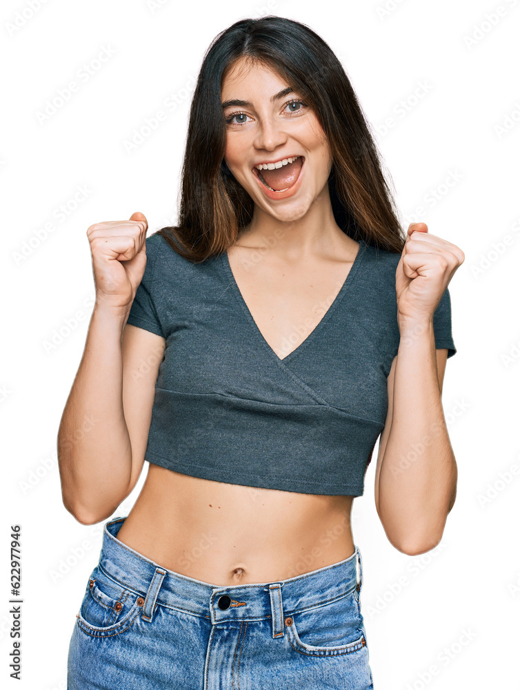 Young beautiful teen girl wearing casual crop top t shirt celebrating surprised and amazed for success with arms raised and open eyes. winner concept. Young beautiful teen girl wearing casual crop top t shirt celebrating surprised and amazed for success with arms raised and open eyes. winner concept.