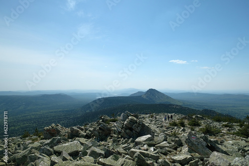 Panorama, landscape. In the foreground are rocks covered with moss, in the background are mountains. Summer, blue sky, day.