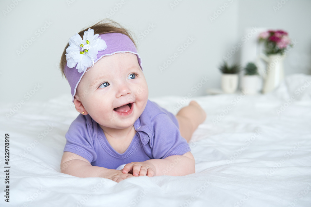 close up baby with blue eyes wearing a purple outfit smiling lying on bed close up baby with blue eyes wearing a purple outfit smiling lying on bed