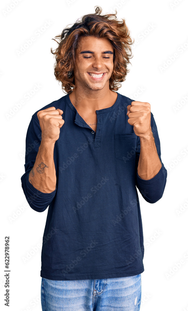 Young hispanic man wearing casual clothes very happy and excited doing winner gesture with arms raised, smiling and screaming for success. celebration concept. Young hispanic man wearing casual clothes very happy and excited doing winner gesture with arms raised, smiling and screaming for success. celebration concept.