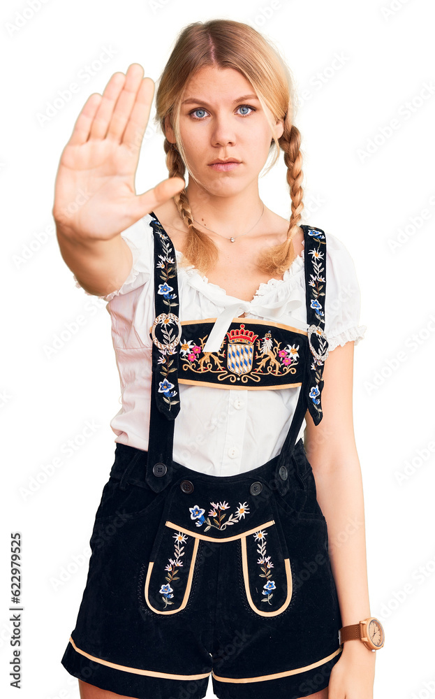 Young beautiful blonde woman wearing oktoberfest dress doing stop sing with palm of the hand. warning expression with negative and serious gesture on the face. Young beautiful blonde woman wearing oktoberfest dress doing stop sing with palm of the hand. warning expression with negative and serious gesture on the face.