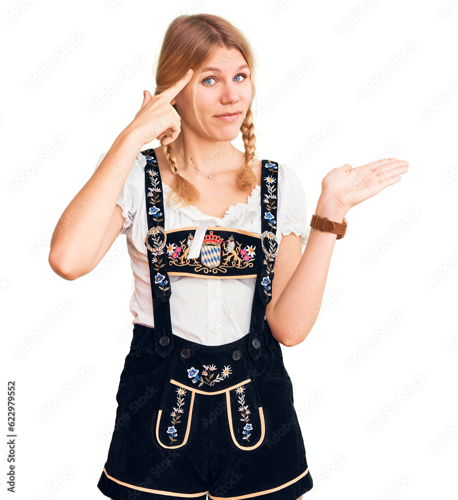 Young beautiful blonde woman wearing oktoberfest dress confused and annoyed with open palm showing copy space and pointing finger to forehead. think about it.
