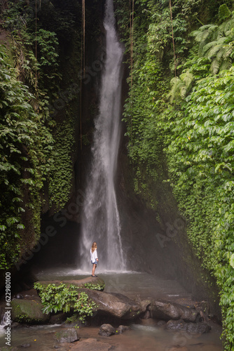Travel lifestyle. Young traveler woman at waterfall in tropical forest. Leke Leke waterfall  Bali  Indonesia