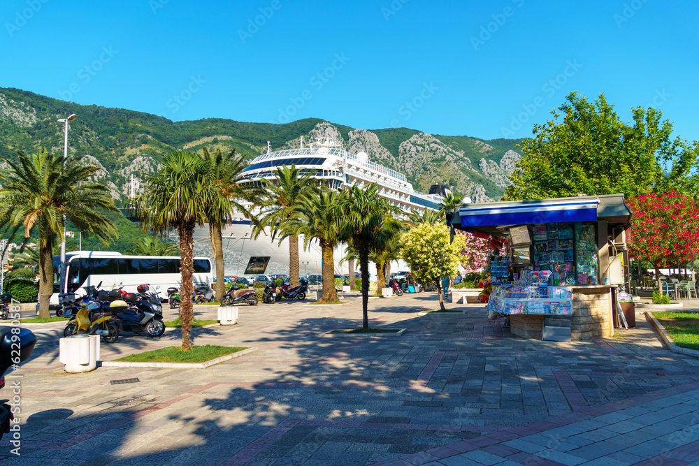 view of a tourist spot near the pier with a cruise liner on the street of Kotor Montenegro, bright sunny day, mountains and palm trees on the shore of the Bay of Kotor, travel