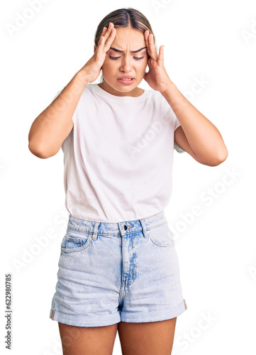 Young beautiful blonde woman wearing casual white tshirt with hand on head for pain in head because stress. suffering migraine. photo