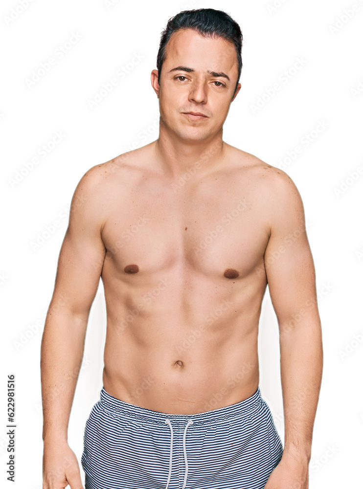 Handsome young man wearing swimwear shirtless looking sleepy and tired, exhausted for fatigue and hangover, lazy eyes in the morning. Handsome young man wearing swimwear shirtless looking sleepy and tired, exhausted for fatigue and hangover, lazy eyes in the morning.