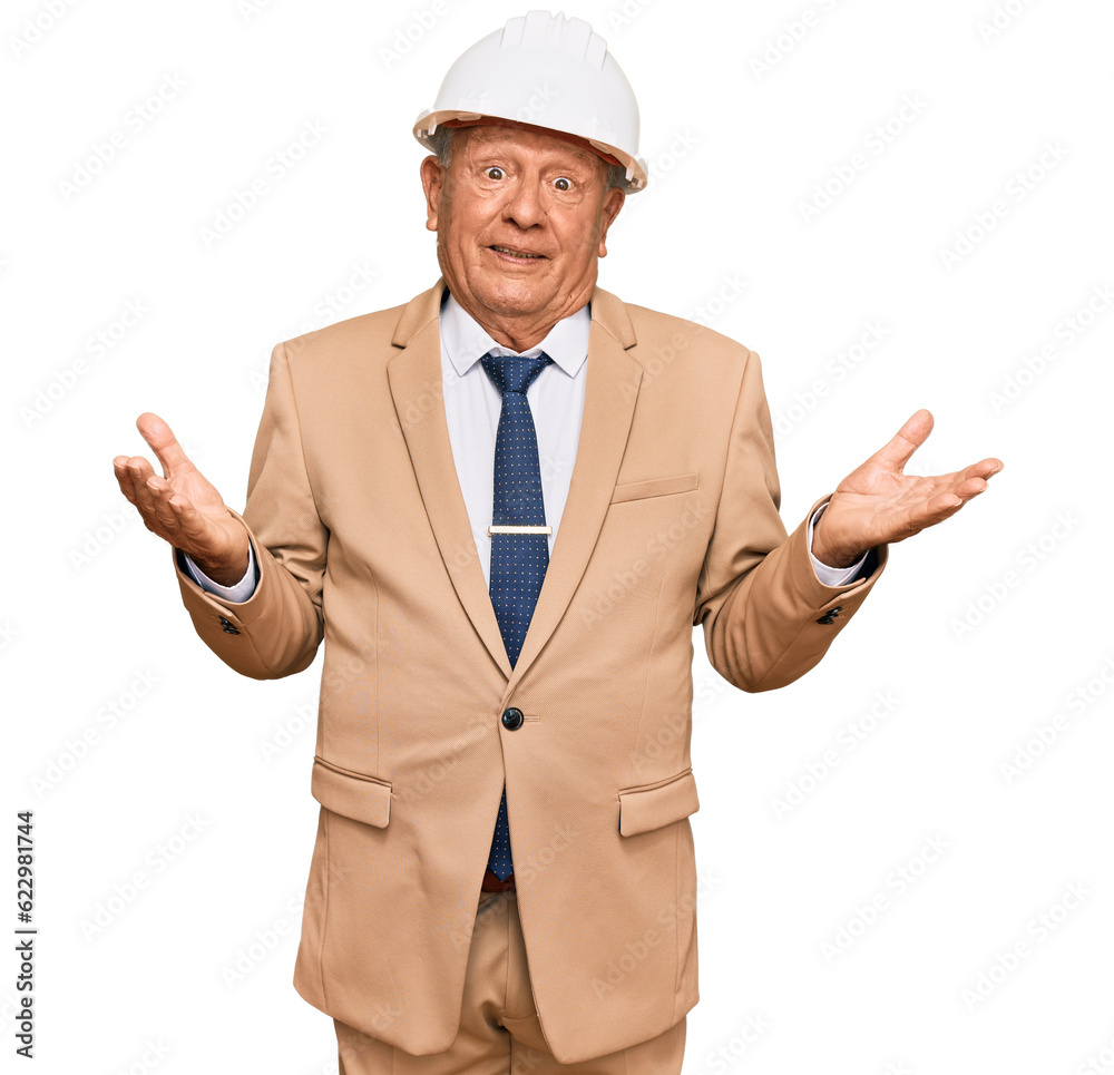 Senior caucasian man wearing architect hardhat clueless and confused expression with arms and hands raised. doubt concept.