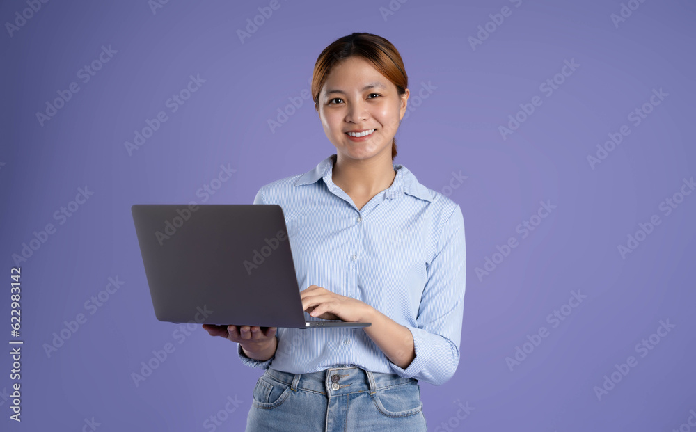 image of young asian business girl using laptop on purple background image of young asian business girl using laptop on purple background