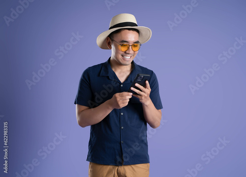 portrait of asian man traveling using phone on purple background