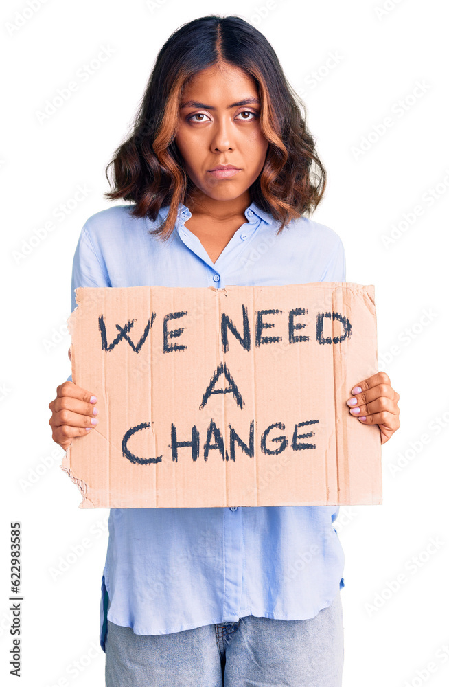 Young beautiful mixed race woman holding we need a change banner thinking attitude and sober expression looking self confident