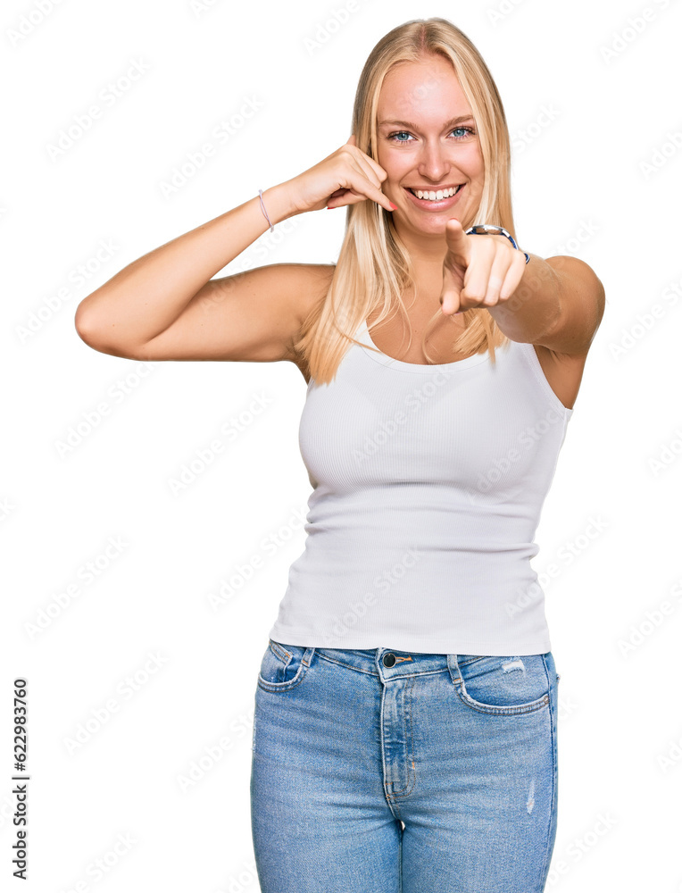 Young blonde girl wearing casual style with sleeveless shirt smiling doing talking on the telephone gesture and pointing to you. call me. Young blonde girl wearing casual style with sleeveless shirt smiling doing talking on the telephone gesture and pointing to you. call me.