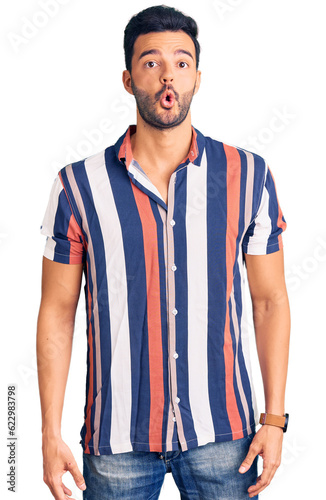 Young handsome hispanic man wearing casual summer shirt scared and amazed with open mouth for surprise, disbelief face