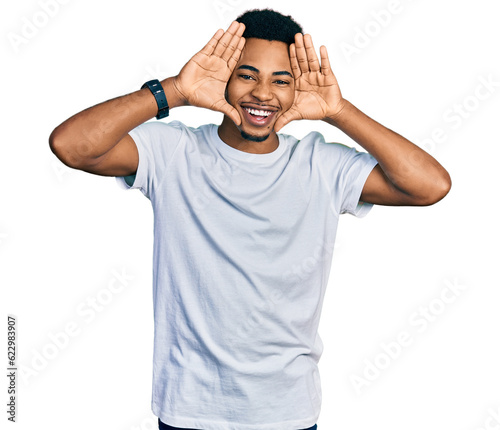 Young african american man wearing casual white t shirt smiling cheerful playing peek a boo with hands showing face. surprised and exited