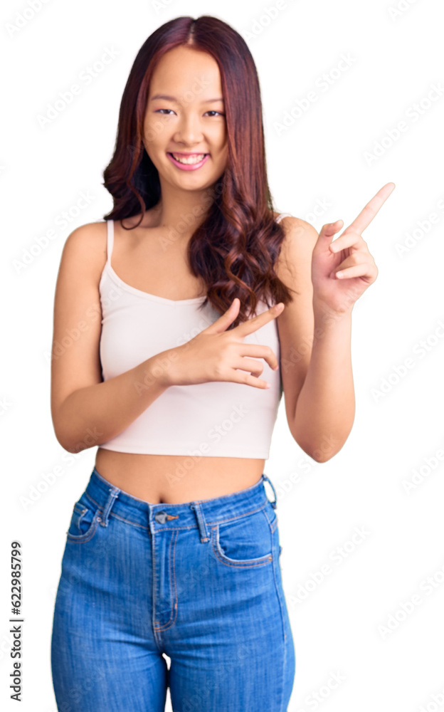 Young beautiful chinese girl wearing casual clothes smiling and looking at the camera pointing with two hands and fingers to the side. Young beautiful chinese girl wearing casual clothes smiling and looking at the camera pointing with two hands and fingers to the side.