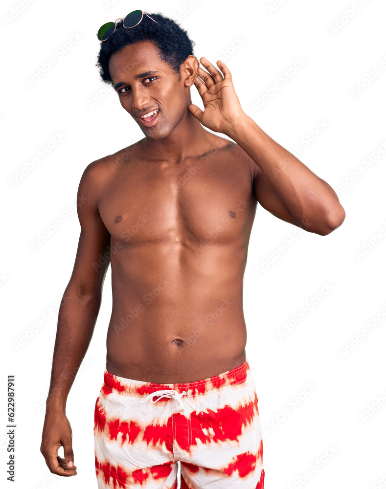 Fototapeta premium African handsome man wearing swimsuit and sunglasses smiling with hand over ear listening an hearing to rumor or gossip. deafness concept.