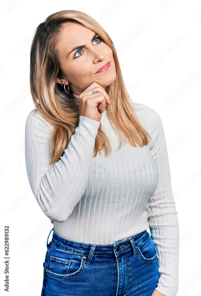 Young blonde woman wearing casual clothes thinking concentrated about doubt with finger on chin and looking up wondering Young blonde woman wearing casual clothes thinking concentrated about doubt with finger on chin and looking up wondering