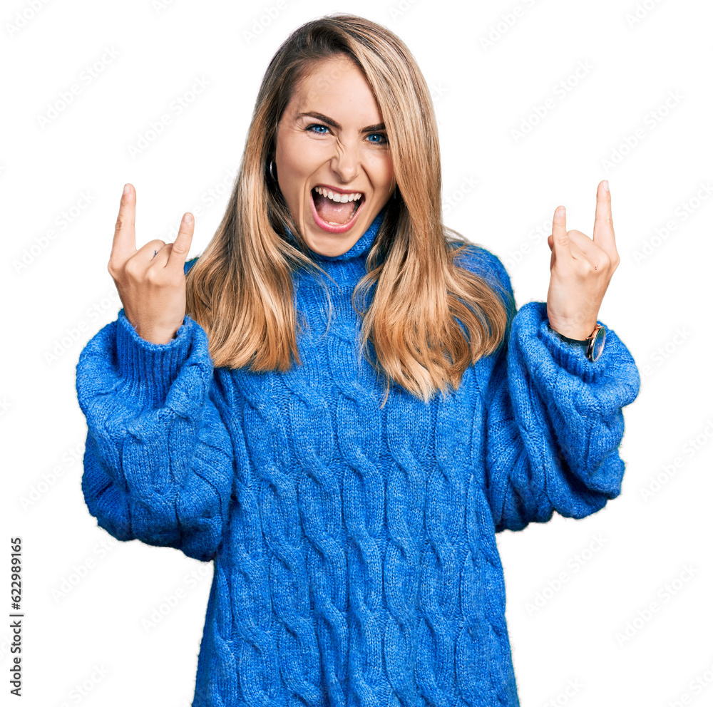 Young blonde woman wearing casual sweater shouting with crazy expression doing rock symbol with hands up. music star. heavy music concept. Young blonde woman wearing casual sweater shouting with crazy expression doing rock symbol with hands up. music star. heavy music concept.