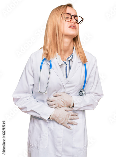 Beautiful caucasian woman wearing doctor uniform and stethoscope with hand on stomach because nausea, painful disease feeling unwell. ache concept.