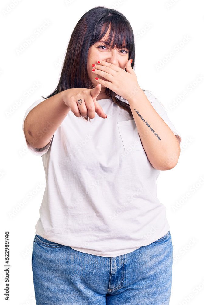 Young plus size woman wearing casual clothes laughing at you, pointing finger to the camera with hand over mouth, shame expression Young plus size woman wearing casual clothes laughing at you, pointing finger to the camera with hand over mouth, shame expression