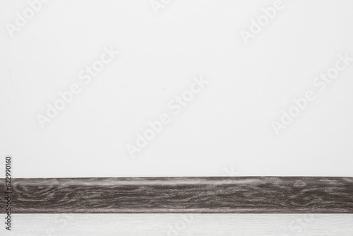 Fotografia Black wooden plinth on laminated floor near white wall indoors