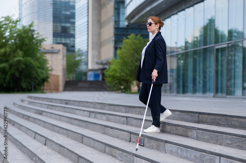 Fényképezés Blind business woman descending stairs with a tactile cane from a business center