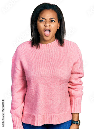 Beautiful hispanic woman wearing casual winter sweater angry and mad screaming frustrated and furious, shouting with anger. rage and aggressive concept.