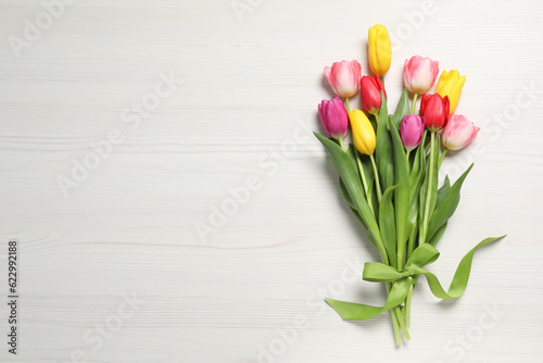 Beautiful tulips on white wooden table, flat lay. Space for text