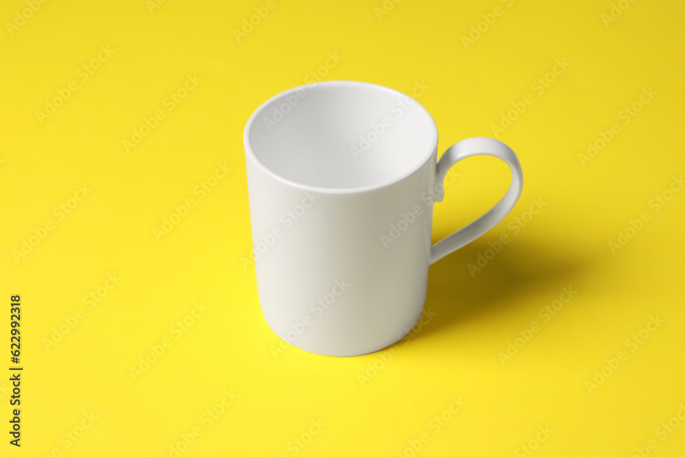 One white ceramic mug on yellow background One white ceramic mug on yellow background