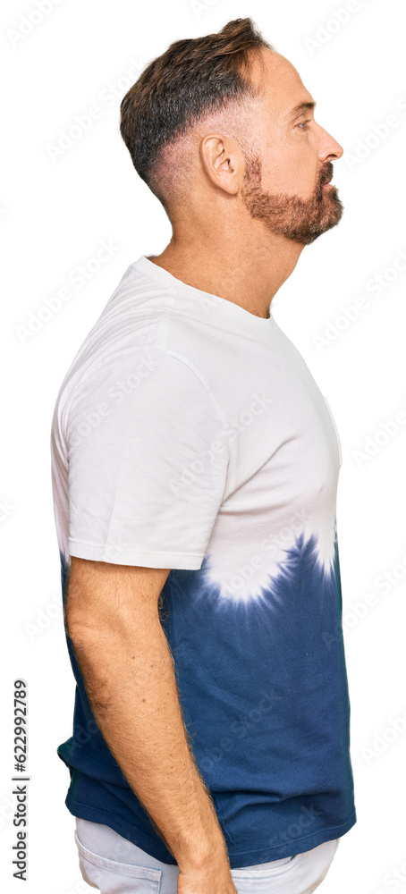 Fototapeta premium Handsome middle age man wearing casual tie dye tshirt looking to side, relax profile pose with natural face with confident smile.