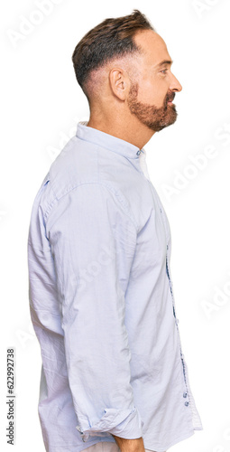 Handsome middle age man wearing business shirt looking to side, relax profile pose with natural face with confident smile.