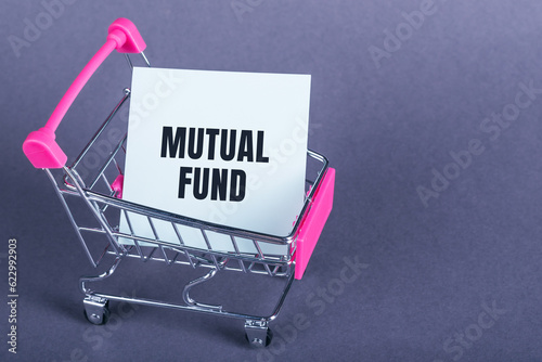 MUTUAL FUND text on a paper stickers in mini shopping trolley on grey background