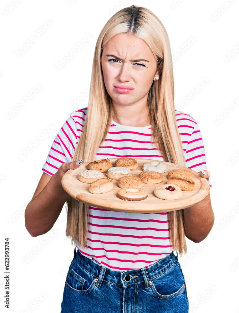 Beautiful blonde woman eating pastries clueless and confused expression. doubt concept. Beautiful blonde woman eating pastries clueless and confused expression. doubt concept.