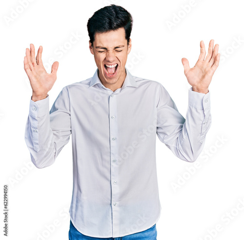 Young hispanic business man wearing business clothes celebrating mad and crazy for success with arms raised and closed eyes screaming excited. winner concept © Krakenimages.com