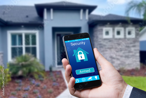 Smartphone with home security app in a hand on the building background.
