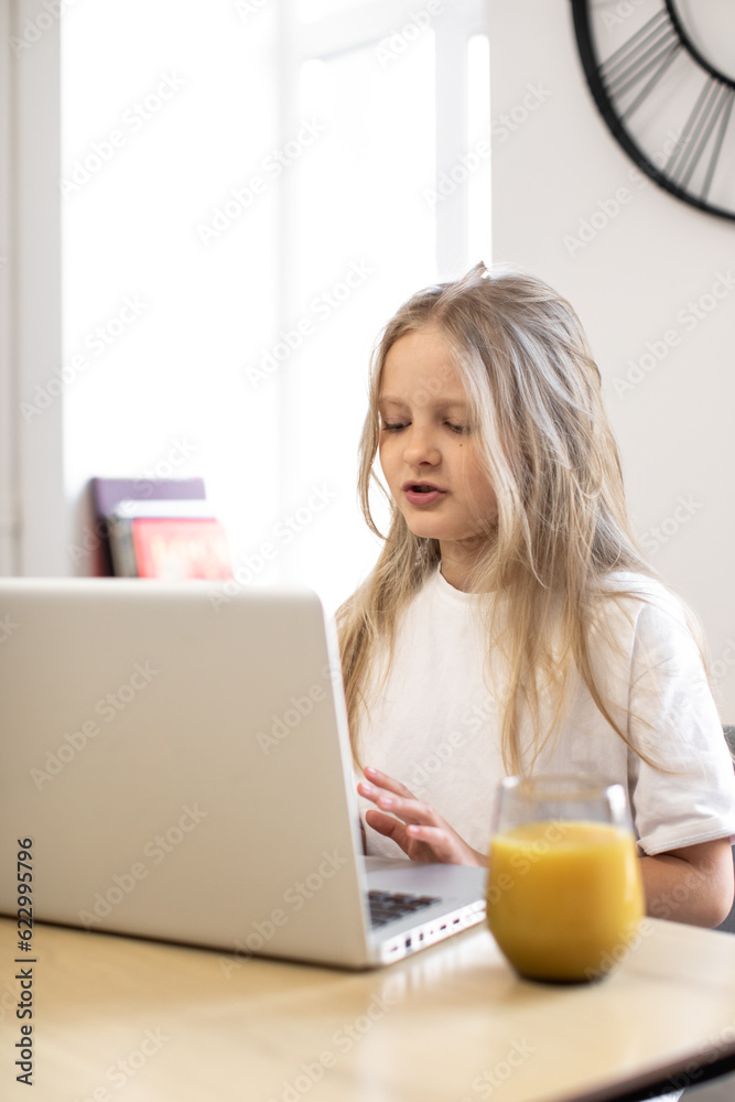 Smiling girl having video call in remote class with teacher using laptop, happy little kid greeting with tutor, learning online on computer, home learning concept Smiling girl having video call in remote class with teacher using laptop, happy little kid greeting with tutor, learning online on computer, home learning concept