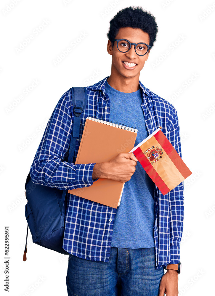Young african american man wearing student backpack holding spanish flag looking positive and happy standing and smiling with a confident smile showing teeth Young african american man wearing student backpack holding spanish flag looking positive and happy standing and smiling with a confident smile showing teeth