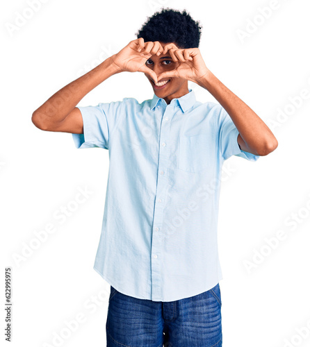 Young african american man wearing casual clothes doing heart shape with hand and fingers smiling looking through sign