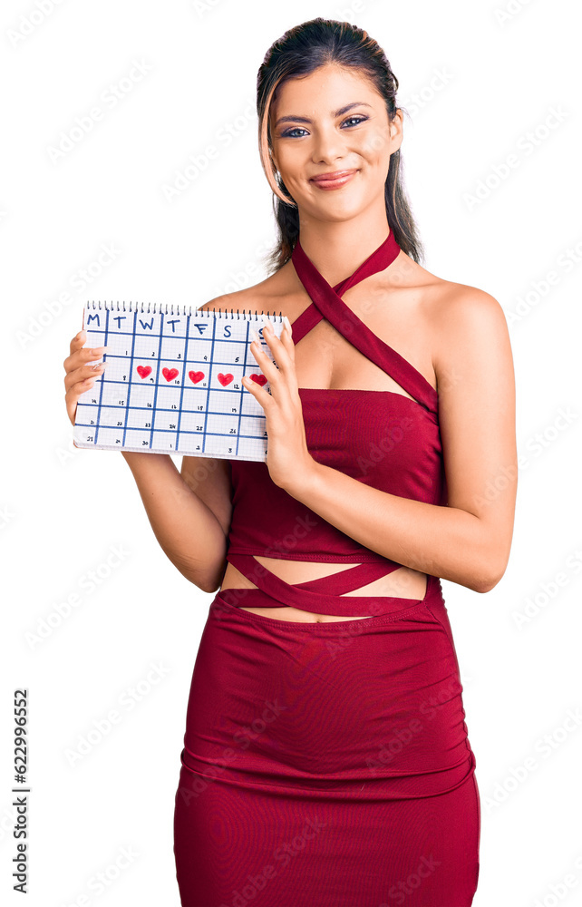 Young beautiful woman holding heart calendar looking positive and happy standing and smiling with a confident smile showing teeth Young beautiful woman holding heart calendar looking positive and happy standing and smiling with a confident smile showing teeth