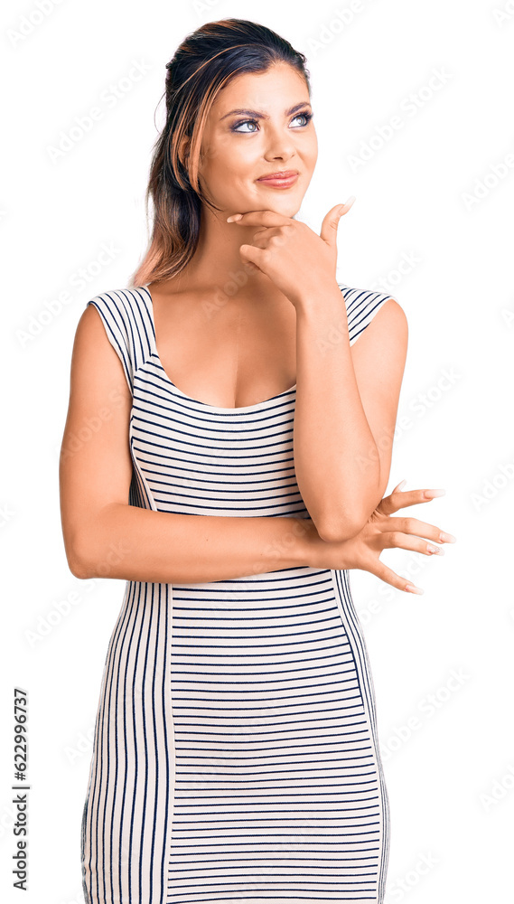 Young beautiful woman wearing casual dress serious face thinking about question with hand on chin, thoughtful about confusing idea Young beautiful woman wearing casual dress serious face thinking about question with hand on chin, thoughtful about confusing idea