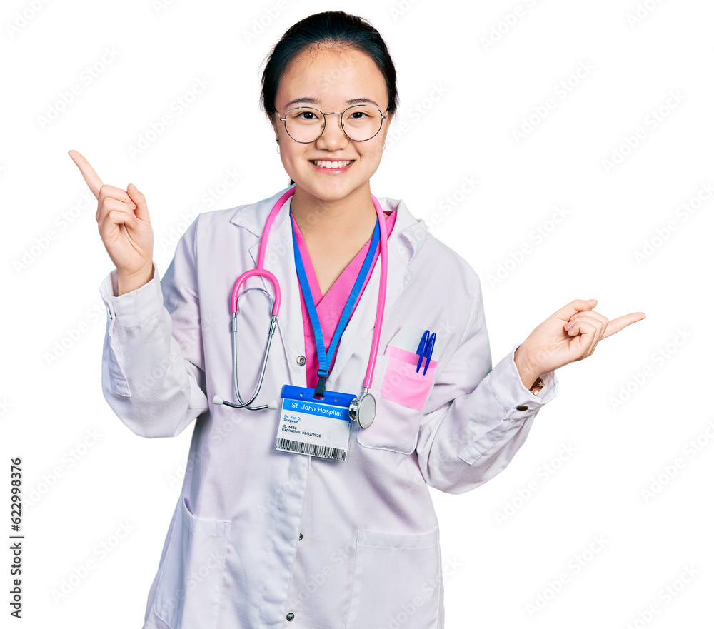 Young chinese woman wearing doctor uniform and stethoscope smiling confident pointing with fingers to different directions. copy space for advertisement Young chinese woman wearing doctor uniform and stethoscope smiling confident pointing with fingers to different directions. copy space for advertisement
