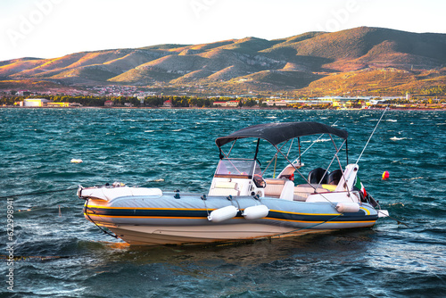 Boat in the Adriatic Sea at sunset, Montenegro . Motorboat at lagoon with mountains on background