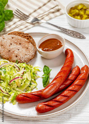sausages with coleslaw salad, bbq sauce on plate